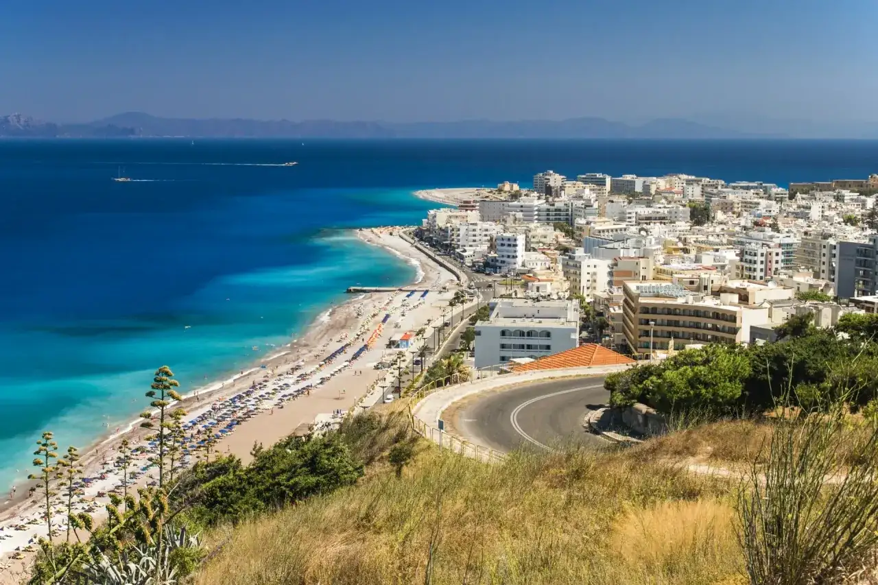 Widok na wybrzeże Rodos z plażą i miastem. Marzy Ci się rejs na Symi z Rodos? Cena może być niższa niż myślisz!